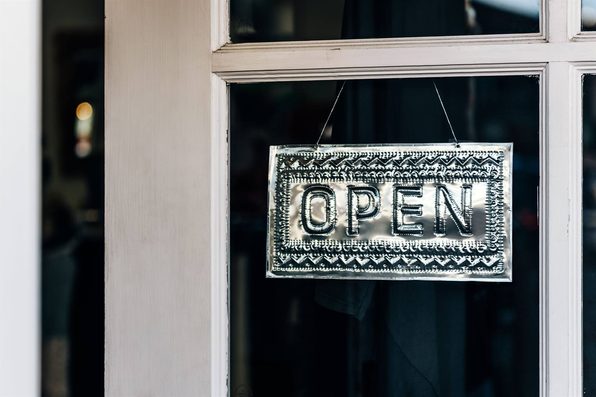 An open sign hanging in a shop door window